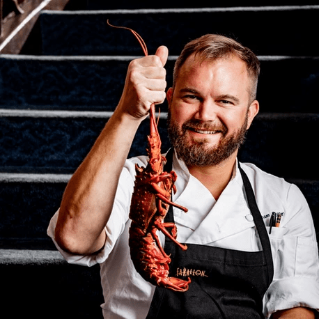 chef smiling holding up spiny lobster