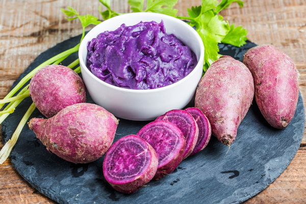 Molokai sweet potato mash with chives and butter in a white bowl