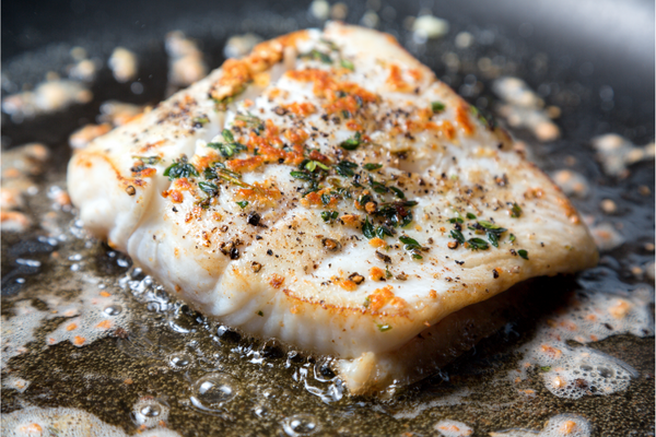 Pan-seared first of the season wild halibut fillets with citrus beurre blanc sauce and chopped parsley on top
