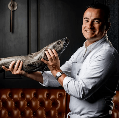 smiling chef holding whole san francisco black cod
