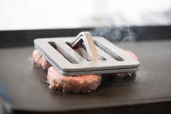 chefs press on hamburgers on the grill smoking