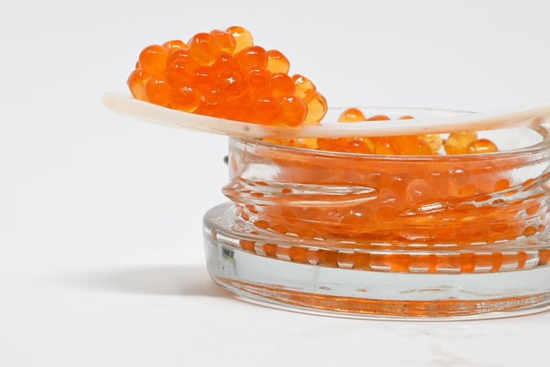 smoked trout roe balancing on mother of pearl caviar spoon on top of a  jar