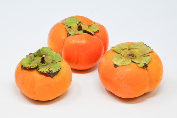 three fuyu persimmons in a triangle